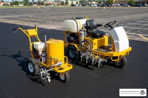 walk-behind and ride-on striping machines lined up on fresh asphalt